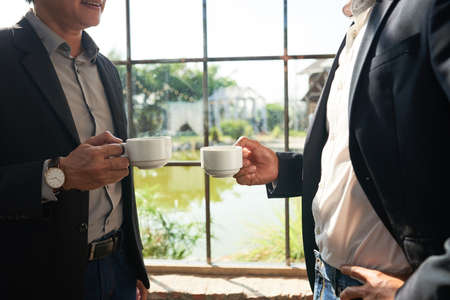 Cropped image of business partners drinking tea at big windowの写真素材