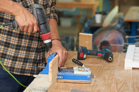 Close-up image of carperter working with wooden plank in his workshop