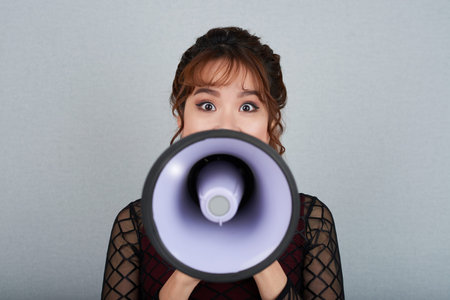 Portrait of Asian yuong woman with loudspeaker looking at camera