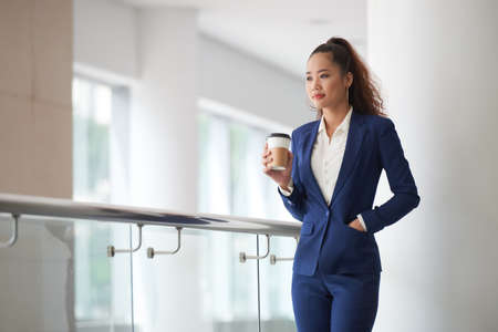 Pensive young Asian business lady drinking coffeeの写真素材