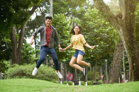 Vietnamese young couple jumping and having fun in the parkの写真素材
