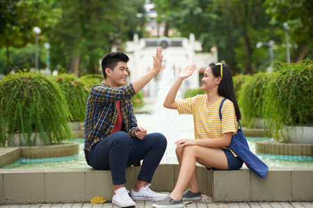 Cheerful Vietnamese yuong people giving each other high fiveの写真素材
