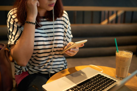 Cropped image of young woman listening to music on her smartphoneの写真素材