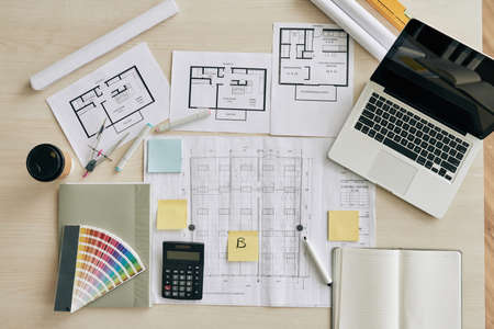 Plans and blueprints on table of interior designer, view from aboveの写真素材