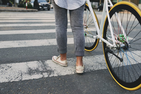 Young woman with bicycle crossing wide road