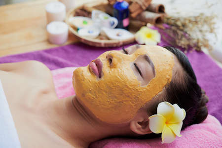 Beautiful Vietnamese young woman relaxing in spa salon with mask on her faceの写真素材