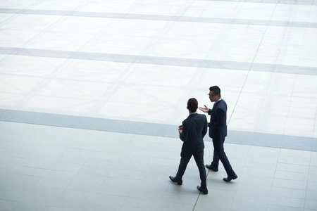 Talking business people with take-out coffee walking in the squareの写真素材