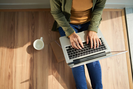Woman sitting on the floor and working on laptop, view from above