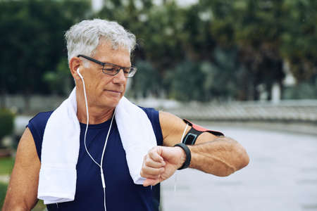 Aged sporty man checking his fitness trackerの写真素材