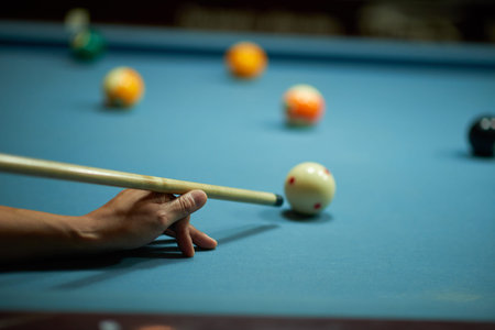 Hands of woman with cue playing snooker, selective focus