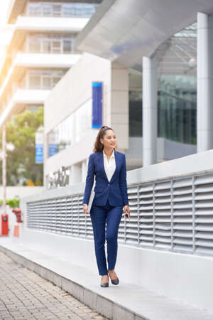 Attravtive young smiling business woman walking in the streetの写真素材