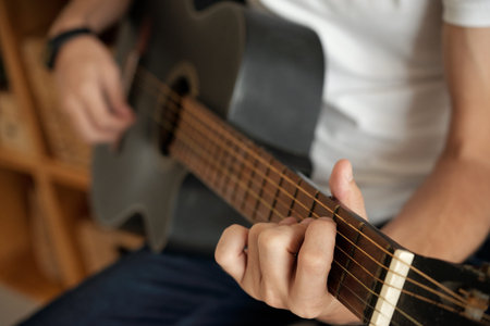 Hands of unrecognizable man playing acoustic guitar