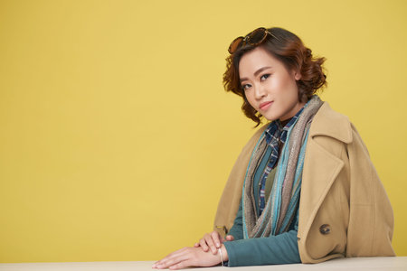 Portrait of beautiful Asian woman wearing stylish clothes on yellow background, copy space to the...