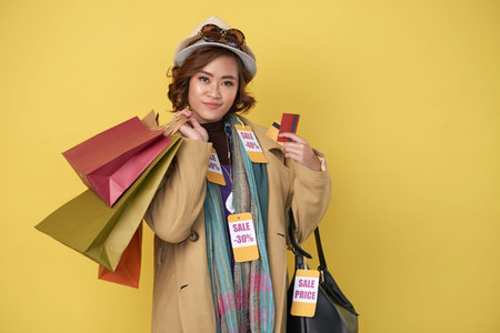 Asian woman posing with shopping bags and credit cards after successful shopping