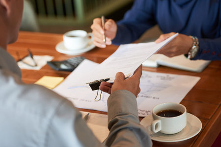 Business partners signing contract while having productive negotiations at cozy small cafe, close-up...
