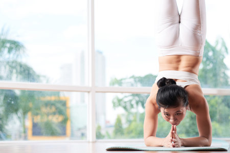 Vietnamese young woman doing handstand on yoga mat