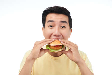 Young fast food lover eating chicken burgerの写真素材