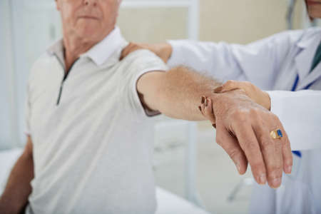 Cropped image of doctor examining patients arm after rehabilitationの写真素材