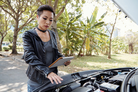 Woman following instructions on digital tablet when checking her car
