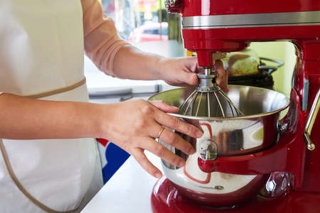 Hands of woman using electric mixer to make the doughの写真素材
