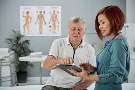 Medical center worker explaining diagnosis to senior patientの写真素材