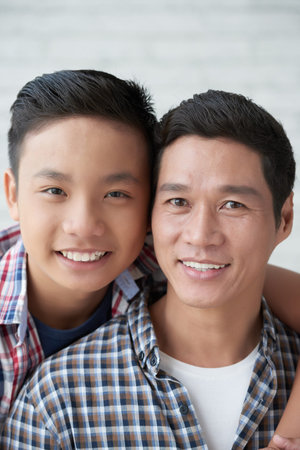 Cheerful teenage Asian boy and his smiling father