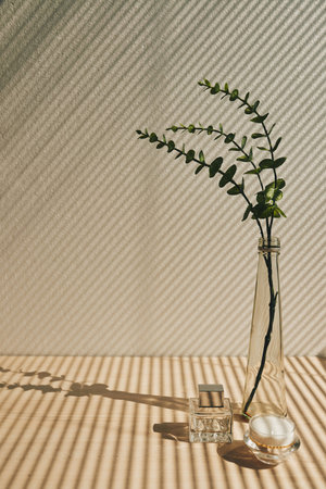 Still life of vase with plant, candle and perfume bottle on table