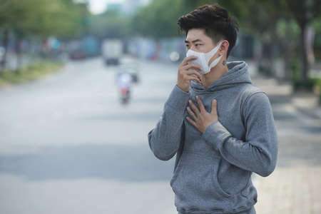 Young Vietnamese man having lungs problems beause of air pollutionの写真素材