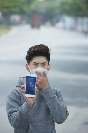 Young Asian man in mask showing air quality index application