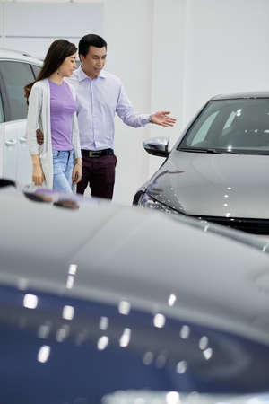Asian man and his wife discussing what car to buyの写真素材