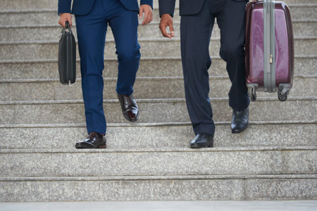 Cropped image of business travelers with luggage walking down the stairs