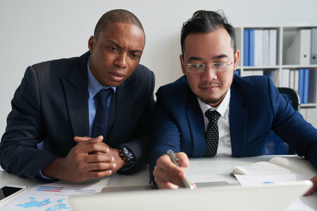 Serious entrepreneurs analyzing information on computer screen