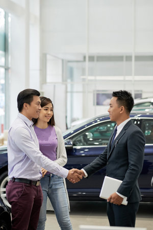 Couple telling thank you to car dealership assistant