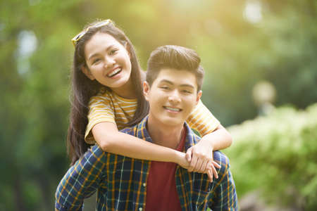 Handsome happy young man giving his girlfriend piggyback rideの写真素材