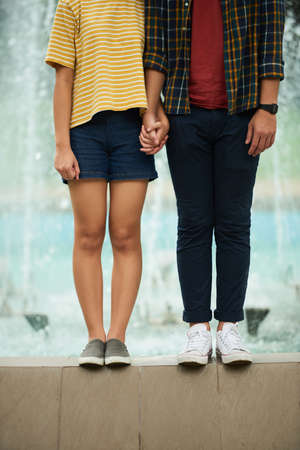Couple holding hands when standing at fountainの写真素材