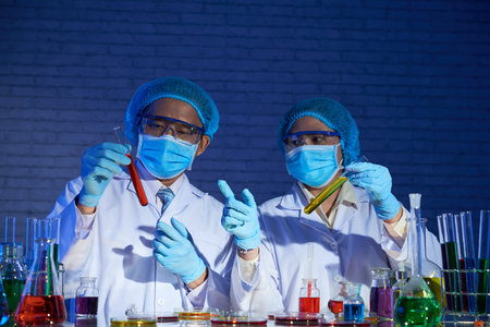 Highly professional medical workers wearing masks and white coats brainstorming on creation of...