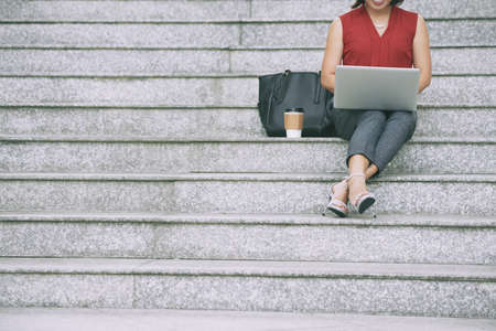 Cropped image of female business executive sitting outdoors and working on laptopの写真素材