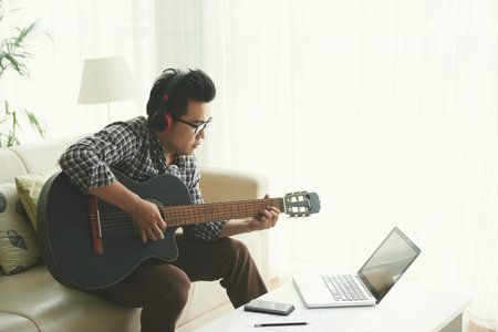 Young man playing guitar and working on new song