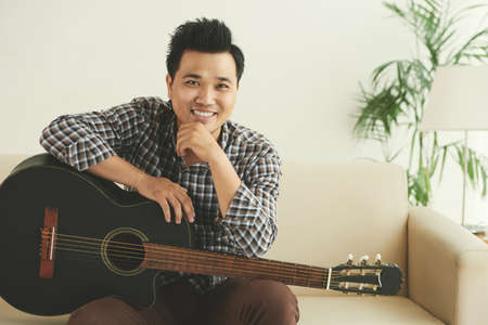 Portrait of happy Vietnamese young man with his guitarの写真素材
