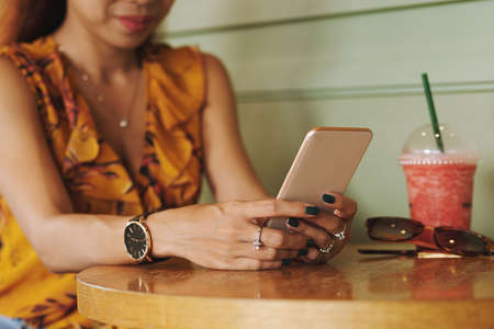 Cropped image of woman sitting in cafe and texting with friendsの写真素材