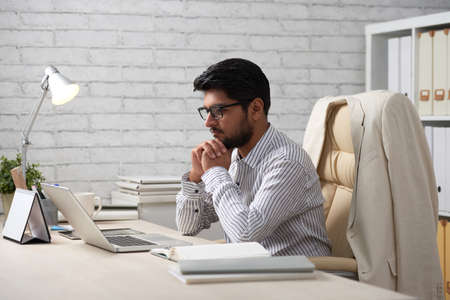 Successful Indian businessman reading e-mails on his laptopの写真素材