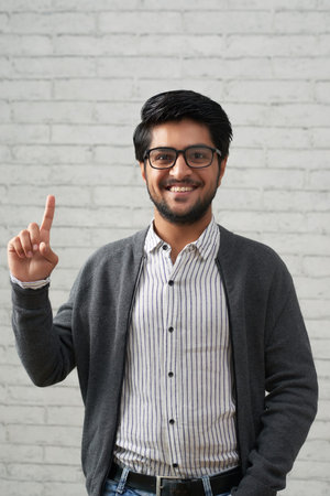 Handsome happy young Indian man having idea
