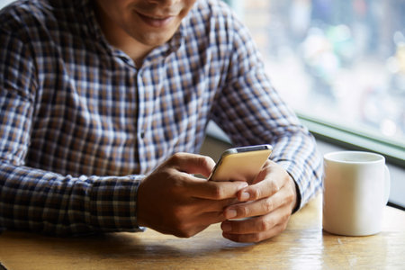 Young man browsing the internet on his cellphone at cafe
