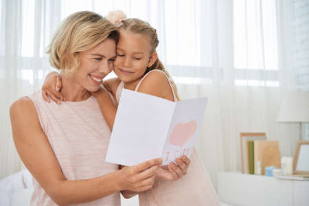 Happy mother reading greeting card from her daughterの写真素材