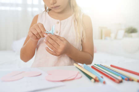 Close-up image of girl making crane out of paperの写真素材