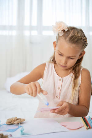 Teenage girl glueing paper hearts on paper cardの写真素材