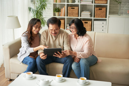 Senior people looking something on touchpad while drinking tea at home