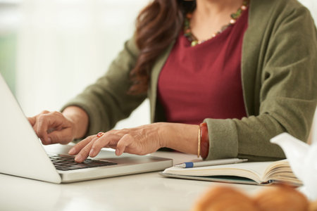 Close-up of senior woman working on laptop at the table
