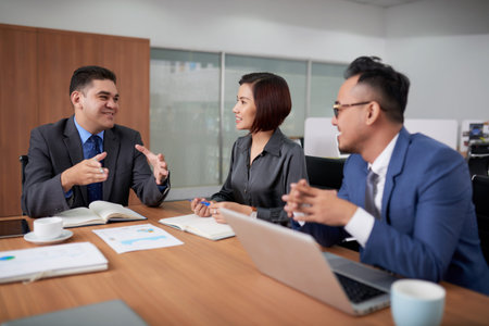 Multi-ethnic team of managers gathered together at spacious meeting room and sharing creative ideas...