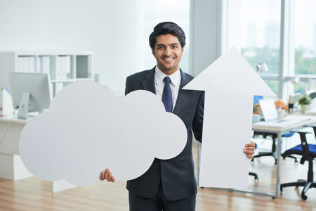 Portrait of smiling Indian businessman with signs standing at office